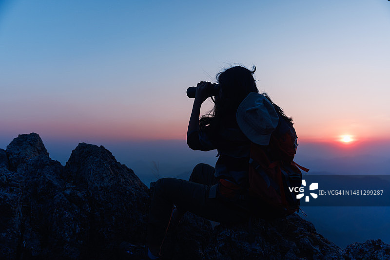 亚洲女背包客在山顶上使用双筒望远镜图片素材