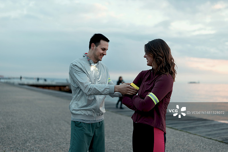 男人为跑步伙伴穿戴夜间装备图片素材