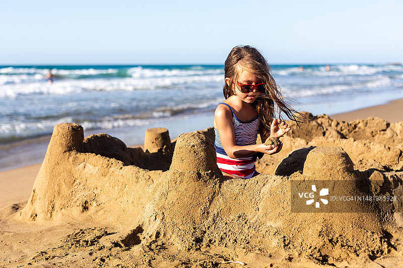 女孩在沙滩上堆沙堡图片素材