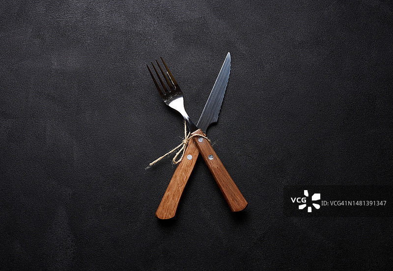 黑色背景上的木柄叉子和刀子，顶部视图图片素材