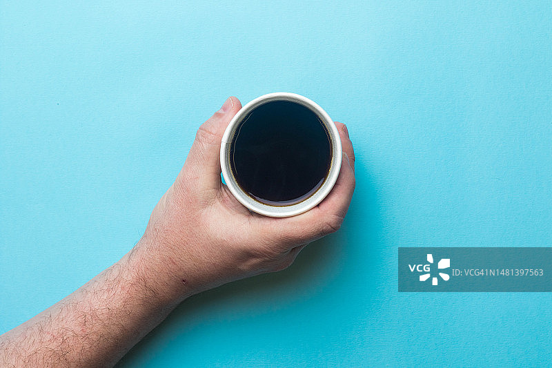 男人在蓝色背景上手持咖啡杯的裁剪图，英国伦敦图片素材