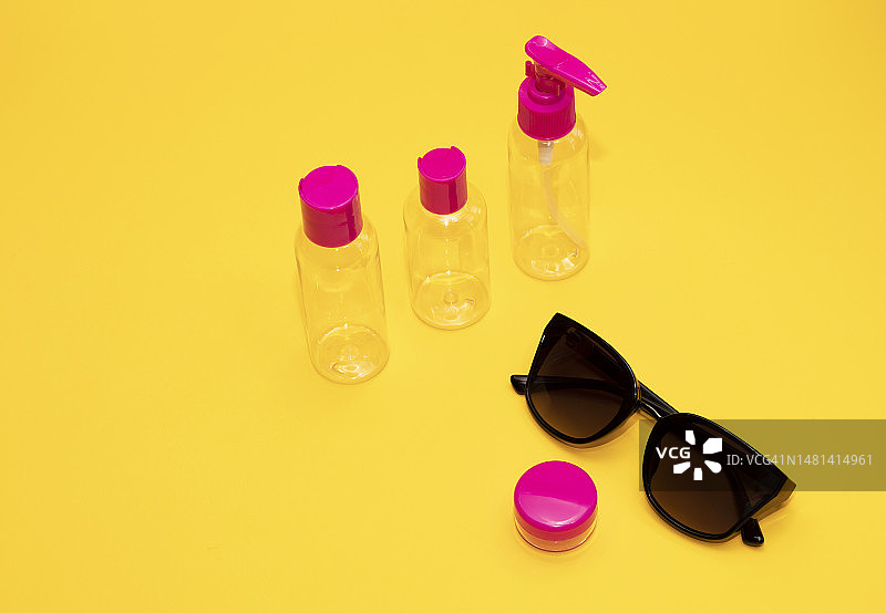 飞机行李箱上的紫红色瓶子和太阳镜图片素材