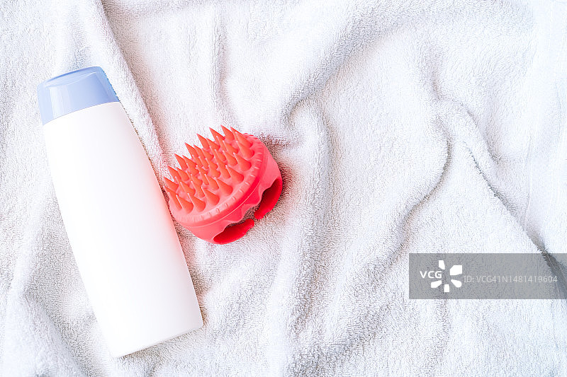 白色毛巾上的洗发水和头皮按摩器图片素材
