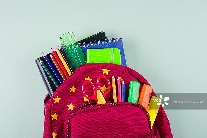 返校季概念红色背包与不同彩色文具在粉绿色背景上，哈萨克斯坦图片素材