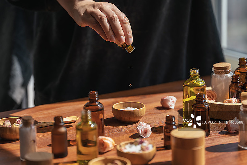 女人在木桌上准备芳香盐，用精油自制香水，护肤品，天然化妆品图片素材