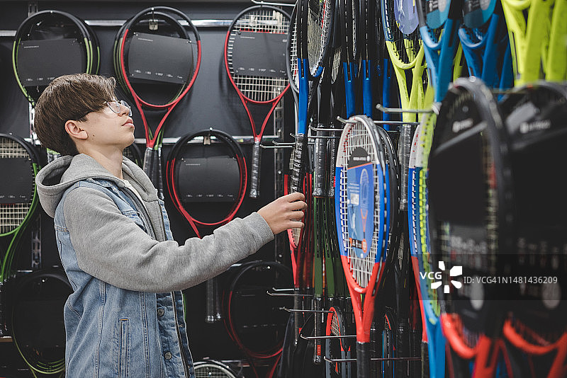 在体育用品店挑选网球拍的男孩图片素材