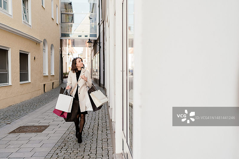 女人手提购物袋，在店面外行走的全身照图片素材