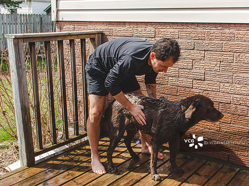 男人给他的狗洗澡图片素材