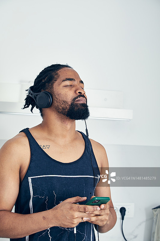 一个戴着耳机、享受智能手机音乐的快乐男人图片素材