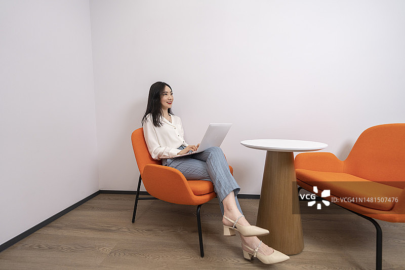 在沙发上用笔记本电脑工作的年轻女子图片素材