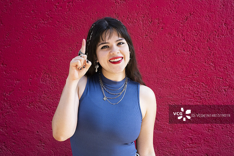 微笑，看着镜头并做出“第一”手势的年轻白人拉丁裔女性图片素材