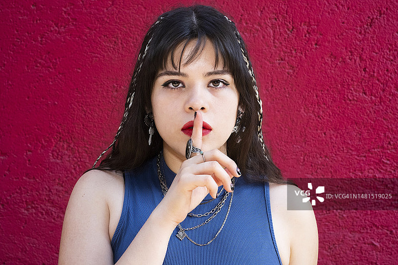 年轻的白人拉丁裔女子用手指放在嘴唇上，示意安静图片素材