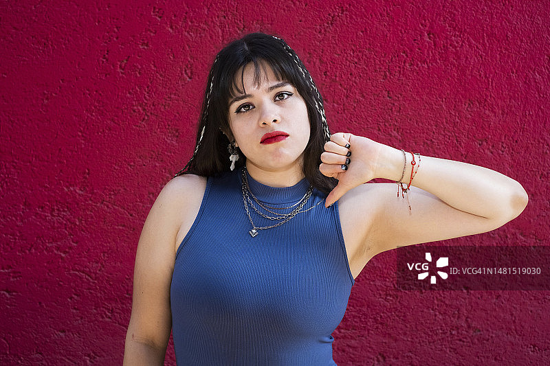 年轻的白人拉丁裔女子看着镜头并竖起大拇指向下图片素材