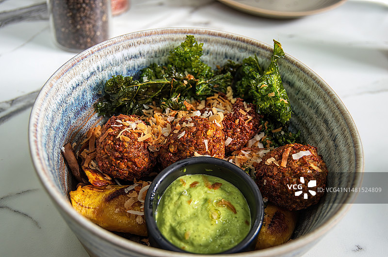 椰子饭配炒蘑菇、炸羽衣甘蓝、甜车前草、红薯和香菜酸橙酱的油炸鹰嘴豆碗图片素材