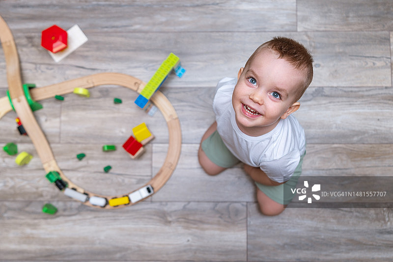 在家里房间的地板上玩玩具火车的快乐宝宝图片素材