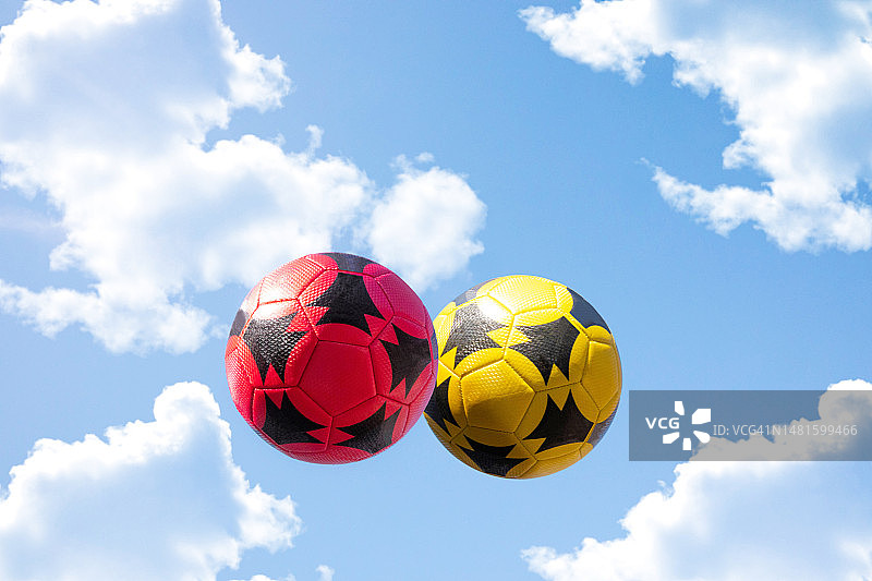 蓝天白云下漂浮的红黄色足球图片素材