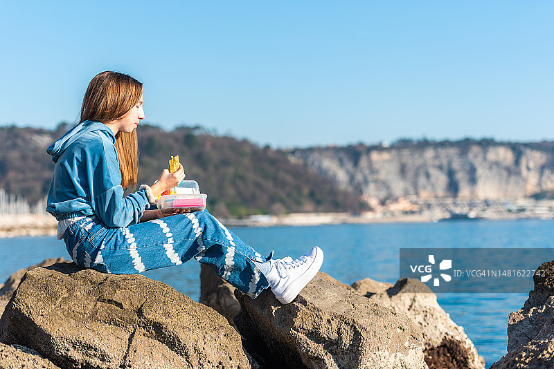 阳光明媚的冬日，少女在海滩享用午餐图片素材