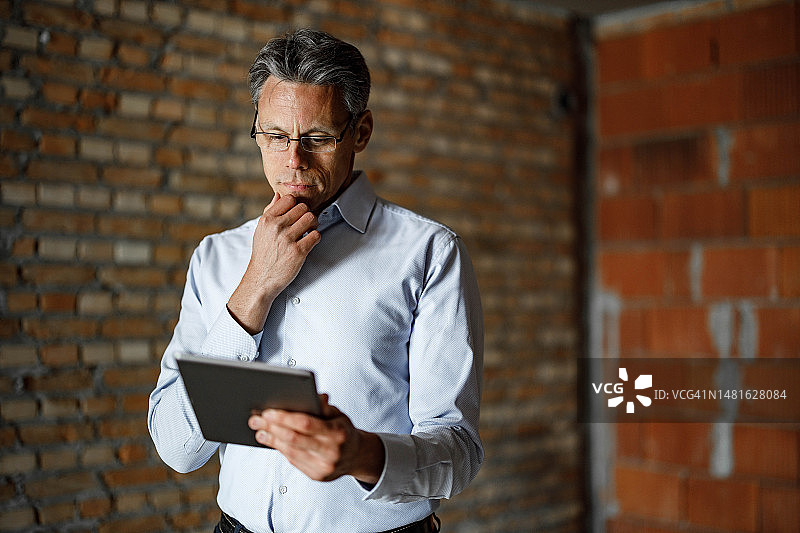 沉思的商人使用数字平板电脑在施工现场图片素材