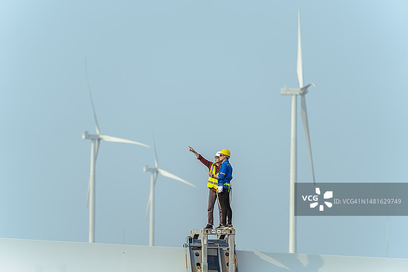 在风力涡轮机农场工作的男工程师和技术员图片素材