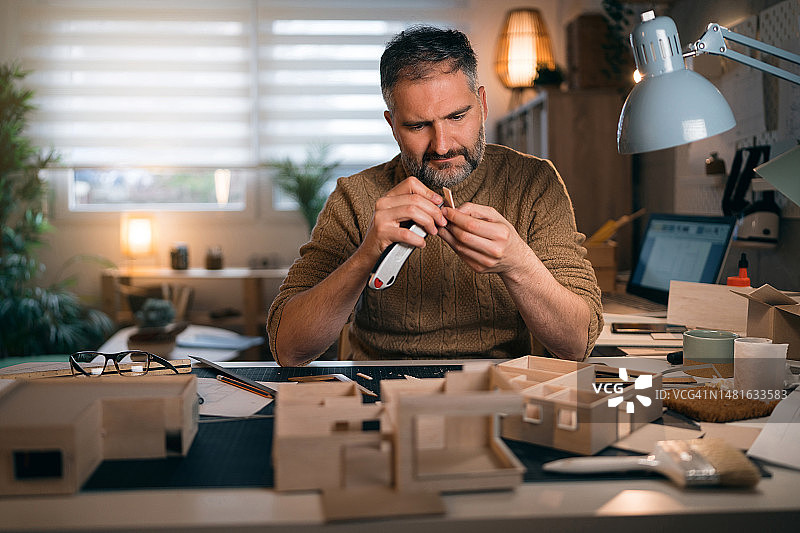 建筑师用手术刀切割建筑模型纸板图片素材