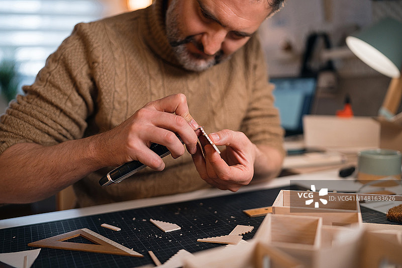 建筑师用手术刀切割建筑模型纸板图片素材