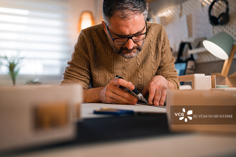 建筑师用手术刀切割建筑模型纸板图片素材