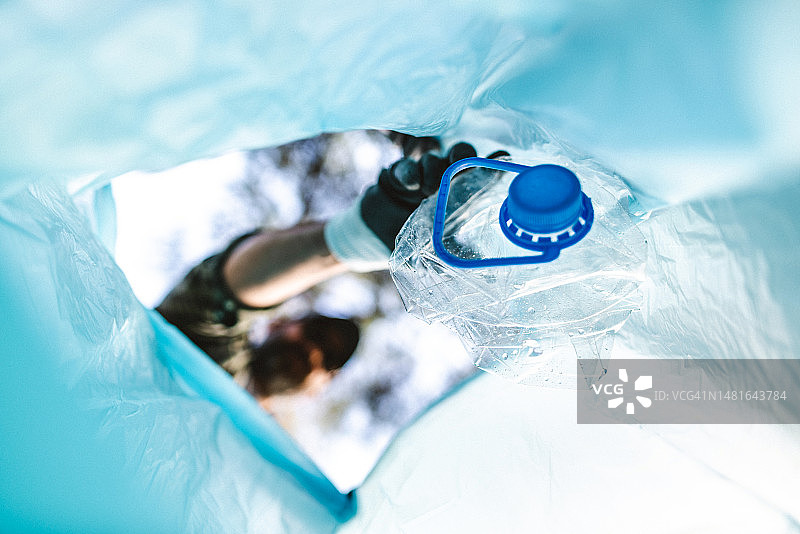 在森林里收集垃圾：塑料容器和瓶子，塑料袋内部视角图片素材