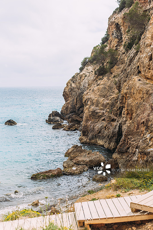 岩石之间的地中海海滩，有木制走道。西班牙巴利阿里群岛伊维萨岛卡拉隆加。图片素材