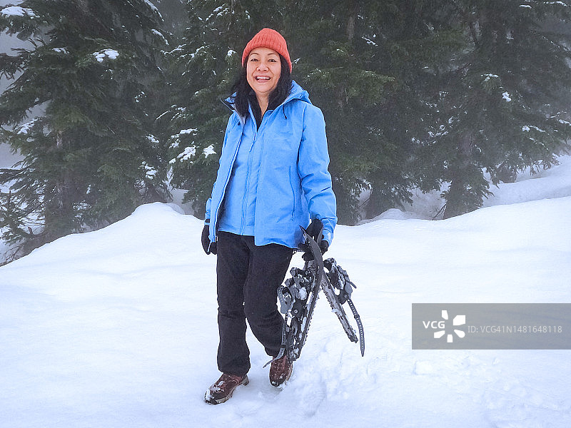 微笑的亚洲60岁以上妇女在森林中步行到雪鞋小径起点图片素材