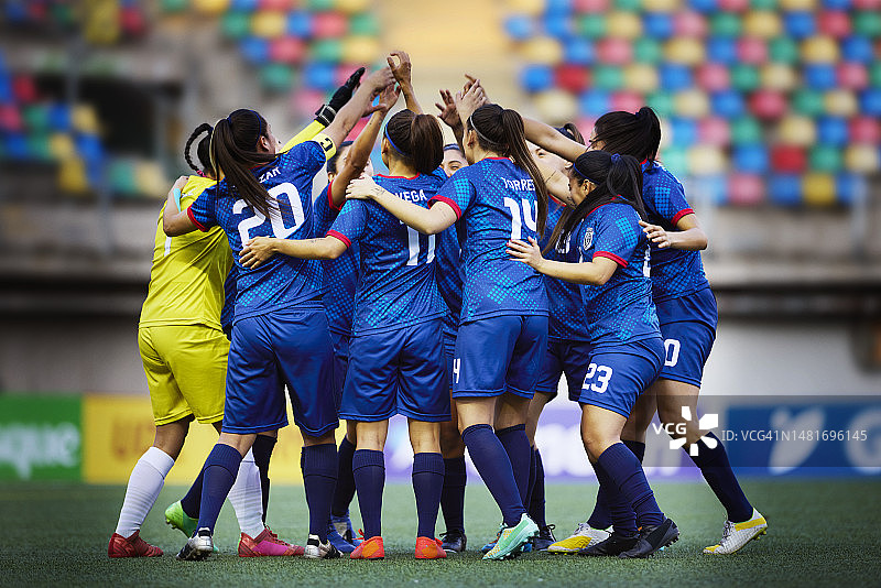 兴奋的女子足球队队员举起手臂围成一圈图片素材