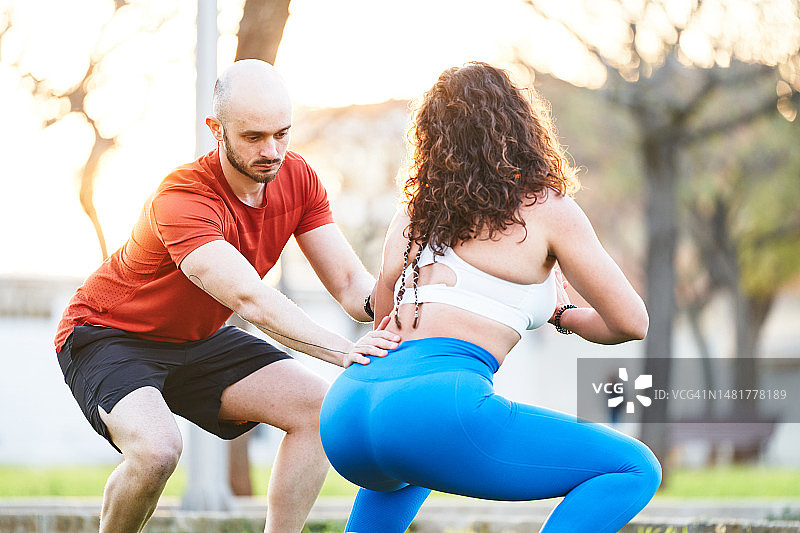 教练向一名妇女讲解正确的深蹲姿势图片素材