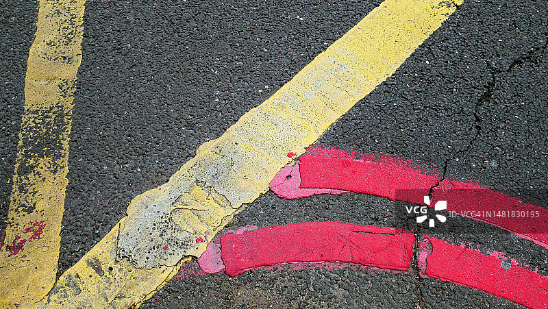 英国伦敦街道上带有黄色和红色线条的斑驳沥青路面图片素材