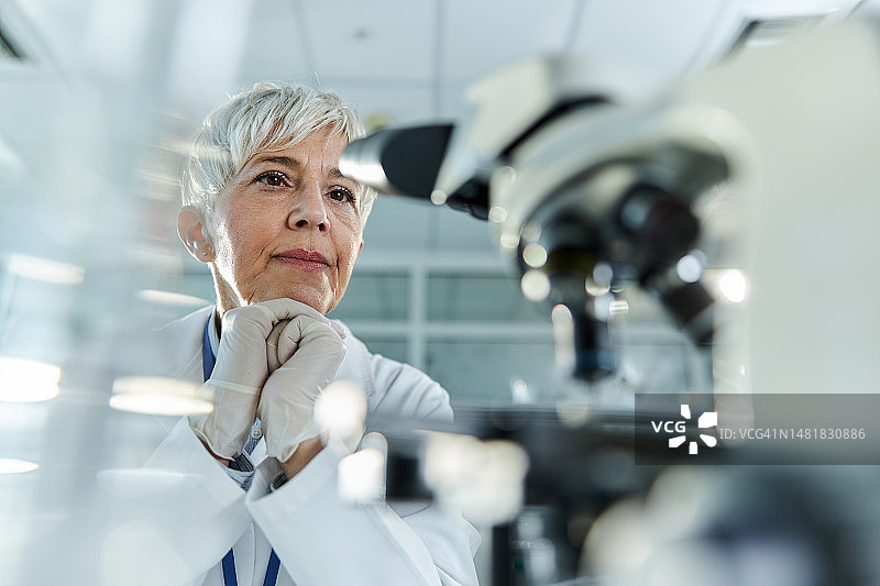 沉思的老年科学家在实验室里用显微镜工作图片素材