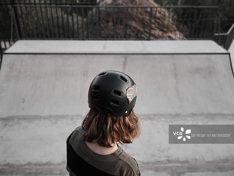 视角：滑板运动员的双脚踩在滑板上，准备滑下斜坡图片素材