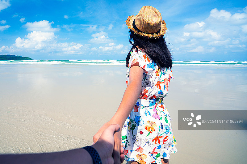 年轻女人牵着男人的手，眺望大海图片素材