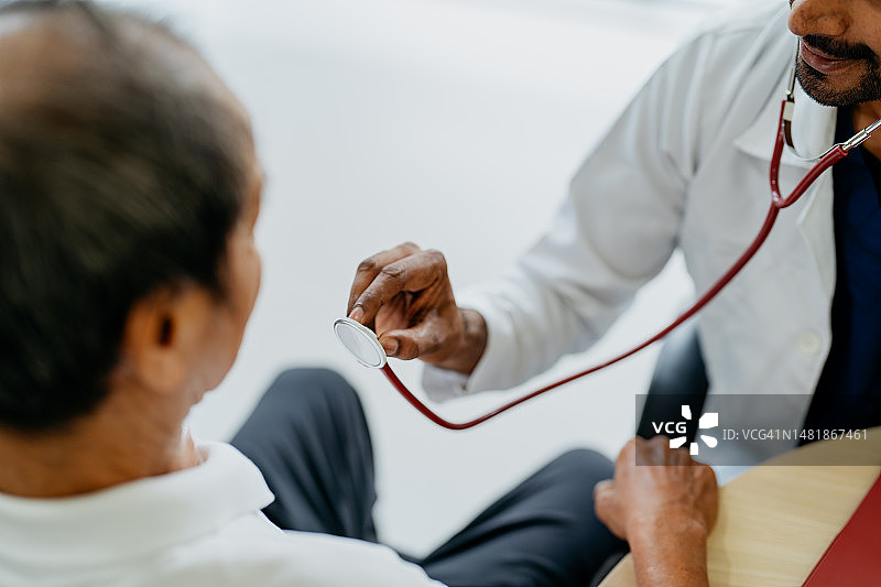 医生在诊所用听诊器检查年长的男病人图片素材