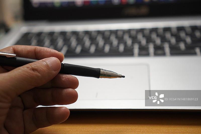 手持钢笔笔记本键盘图片素材