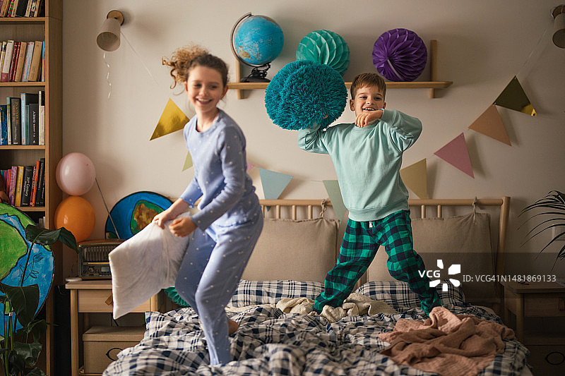 孩子们在床上玩枕头，玩得很开心。图片素材