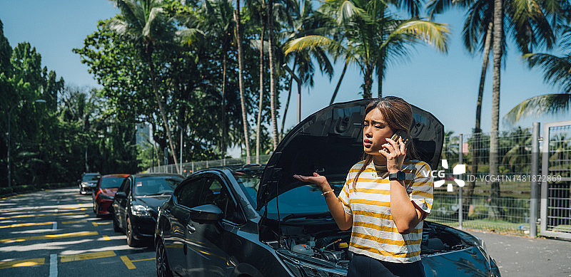 道路救援的挑战：一位年轻亚裔女性和她的智能手机的故事图片素材