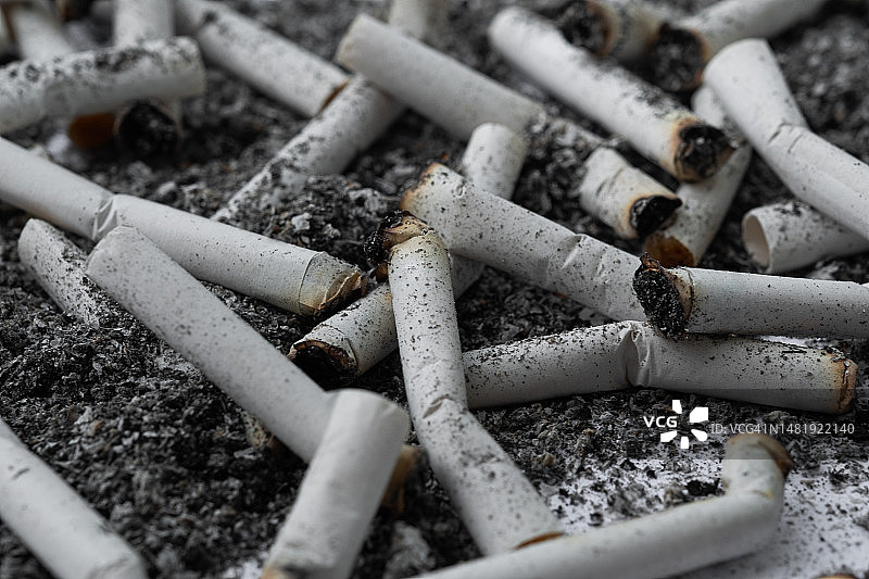 烟灰缸里过滤香烟的剩饭和烟头：吸烟成瘾的概念图片素材