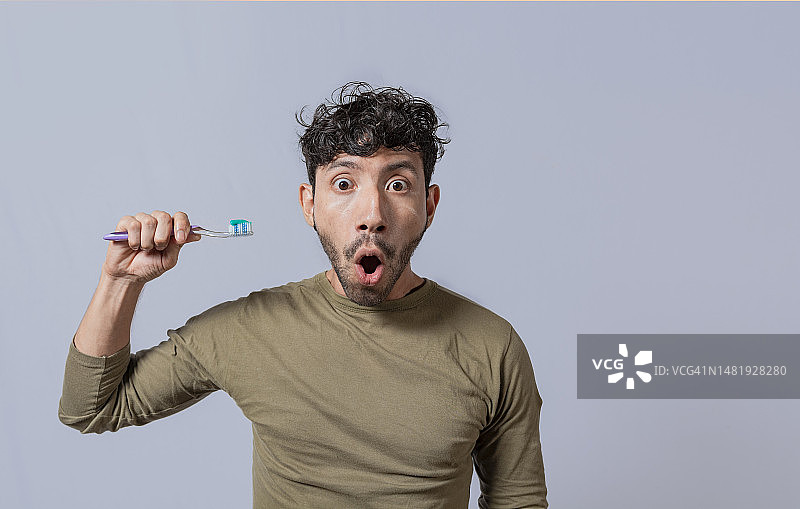 惊讶的年轻男人拿着牙刷和牙膏图片素材