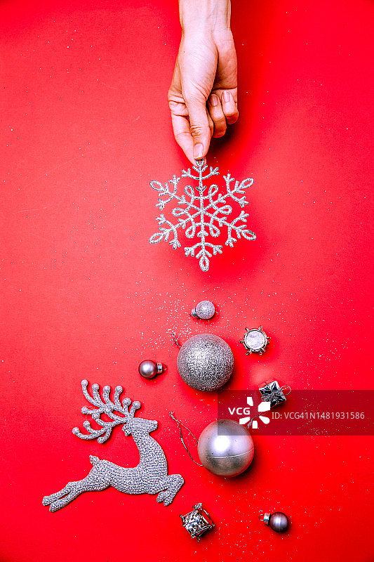女子手持圣诞装饰品，红色背景，意大利科森扎省卡洛佩扎蒂图片素材