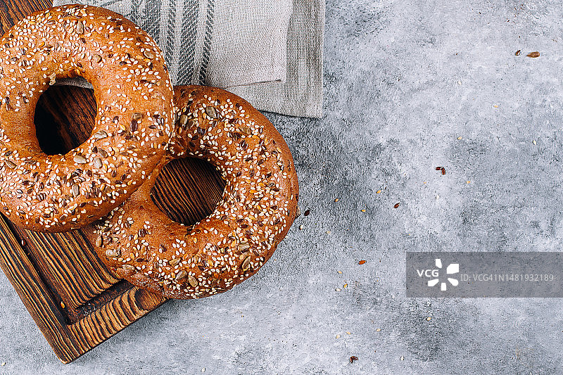 混凝土背景桌上木板上的健康有机全麦百吉饼图片素材