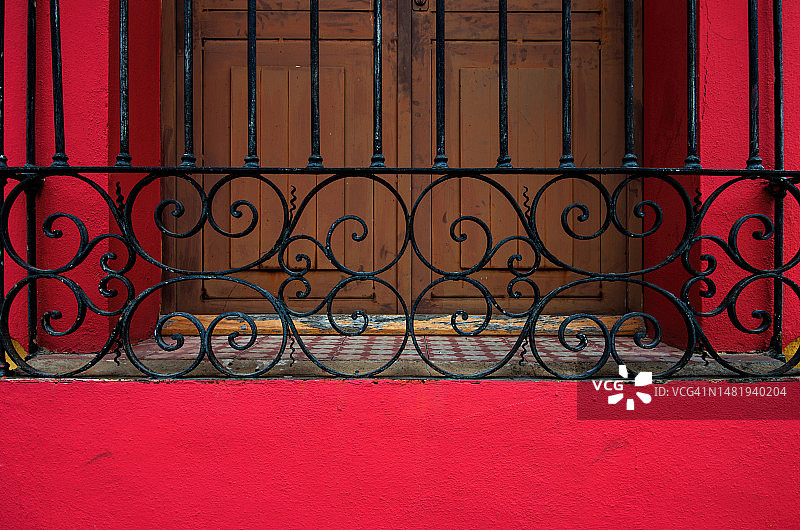 殖民风格红色建筑的木制百叶窗上的装饰性旧金属安全屏图片素材