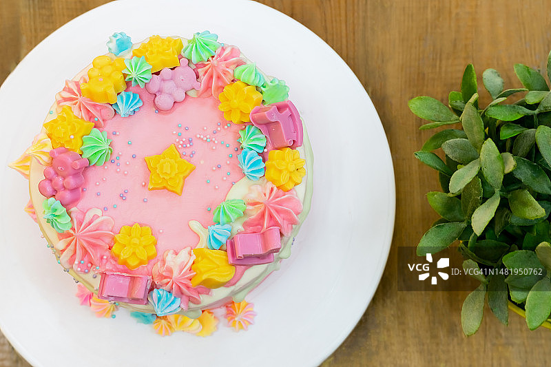 粉色和白色奶油覆盖的派对蛋糕，配彩色蛋白酥皮和巧克力熊图片素材