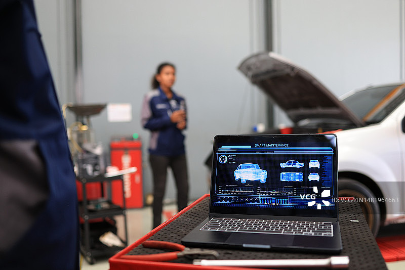 工头使用笔记本电脑管理现代汽车服务系统，控制和管理汽车维护服务系统。图片素材