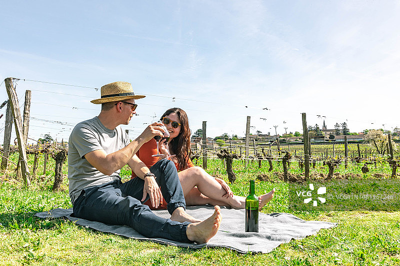 在圣埃米利永葡萄酒产区的葡萄园之间用红酒敬酒的精致夫妇，法国。图片素材