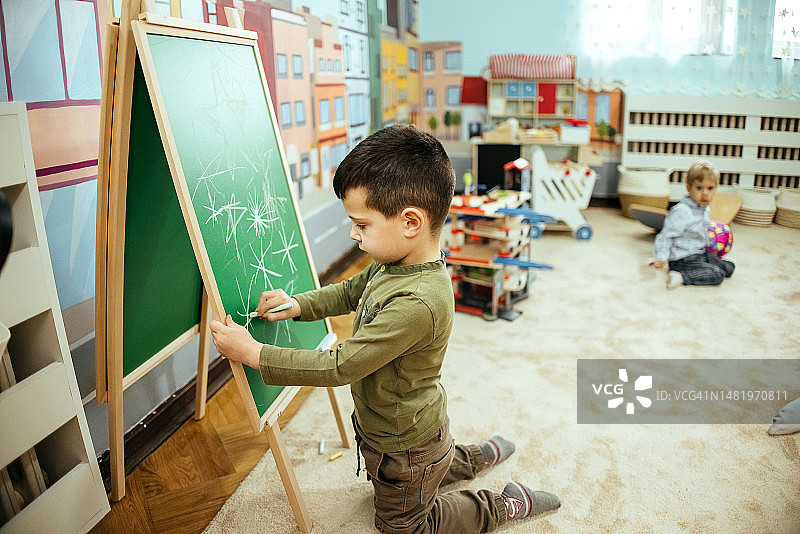 可爱的男孩在黑板上画画图片素材