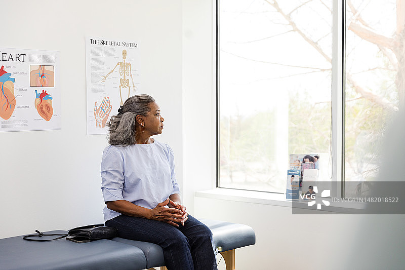 中年妇女坐在检查台上等待医生图片素材
