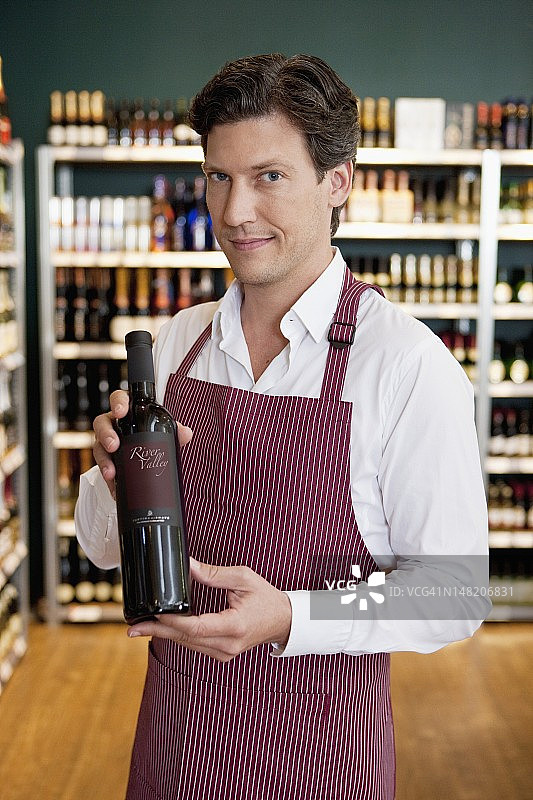 商店售货员手持酒瓶图片素材